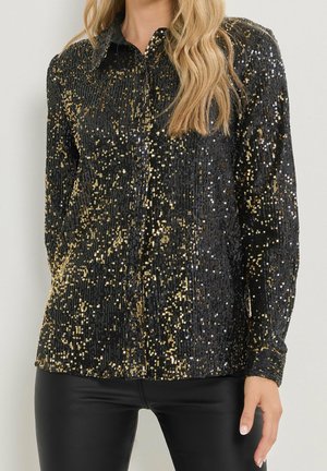 Black button-up shirt covered with gold and silver sequins worn with black leather pants, showing upper torso and hand.