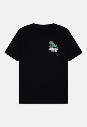 Czarna koszulka z krótkim rękawem z małą zieloną grafiką iguany i napisem "Abercrombie & Fitch Co." na górnej lewej stronie klatki piersiowej.