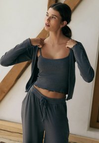 Grau Loungewear-Set mit einem verkürzten Tanktop mit gewelltem Saum und einer Langarm-Cardigan. Weicher, strukturierter Stoff mit elastischem Bund.