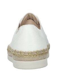 Chaussure slip-on en cuir blanc avec un bord tissé texturé beige et doré autour de la semelle, dotée d'un talon rond et d'un intérieur lisse.