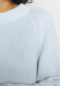 Ljust blått stickat tröja med rund ribbad halsringning, strukturerad mönster och sänkt axelsöm, med en lös passform och fina stygn.