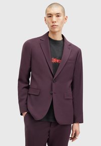 Veste cintrée violette avec deux poches avant et revers en Pointe, fabriquée à partir d'un tissu lisse et structuré. Fermeture à boutons et design élégant.