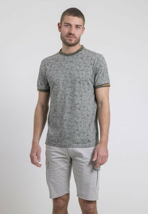 T-shirt gris à manches courtes avec un motif de feuilles, col vert et accent jaune sur la manche ; associé à un short cargo gris clair.