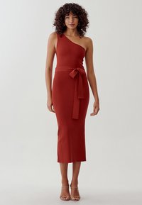 Vestido midi de un solo hombro en color óxido, con una silueta ajustada, detalle de cinturón en la cintura y textura suave. Realza la forma del cuerpo.