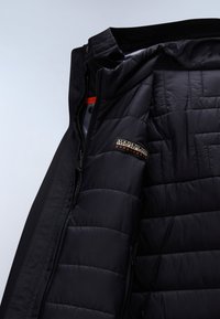 Czarna ocieplana kurtka z widoczną podpinką, zamkiem błyskawicznym i naszywką z logo „Napapijri Geographic” na klatce piersiowej.