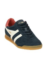 Navy suede sneaker with white stripes, red inner lining, black laces, and gum rubber sole. Brand name "Gola" in gold on the tongue.