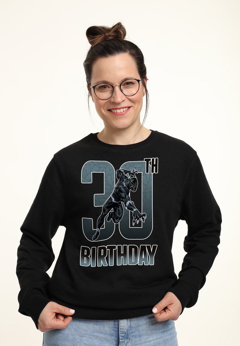Sudadera negra con un gráfico de un superhéroe, texto "30 CUMPLEAÑOS" y números estilizados con un diseño texturizado. Corte casual.