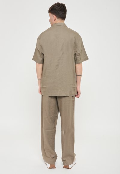 To-part outfit bestående af en kortærmet skjorte med krave og løstsiddende bukser. Fremstillet af let khaki stof med en glat tekstur.