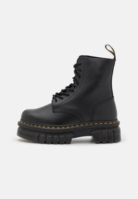 Svart lær lace-up støvel med tykk såle, gul søm, rund tå, og en løftestropp bak for enkel påkledning.