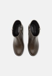 Botas de tobillo de cuero marrón con un acabado suave, punta redonda, cierre con cremallera lateral y un ligero tacón, que presentan un diseño simple y elegante.