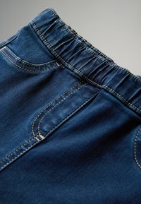 Denimová sukně s tmavě modrou barvou, elastickým pasem, dvěma předními kapsami a viditelným švem. Hladká textura a klasický design.