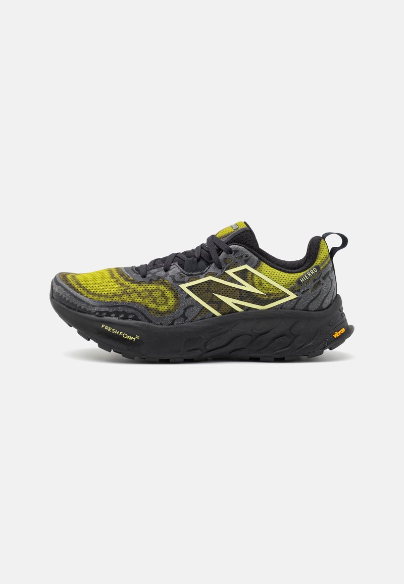 Chaussure de course noire et jaune avec un dessus texturé, arborant un logo 'N' bien en vue, une semelle amortie et un design à motifs.