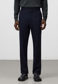 Pantaloni blu scuro realizzati in tessuto strutturato, caratterizzati da un design a gamba dritta, due tasche anteriori e una chiusura a bottone in vita.