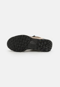 Scarpa da trail con suola in gomma nera texturizzata, caratterizzata da un motivo a geometria per una migliore aderenza e una tomaia solida color sabbia per la massima durata.