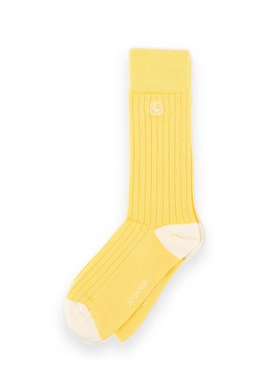 Calcetín amarillo acanalado con talón y puntera blancos, con un pequeño logo circular blanco cerca del puño superior.