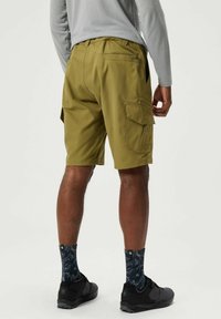 Khaki Cargo-Shorts mit mehreren Seitentaschen, glattem Stoff und einem taillierten Schnitt, kombiniert mit gemusterten marineblauen Socken und schwarzen Schuhen.