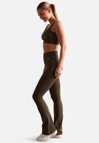 Soutien-gorge de sport côtelé vert olive et leggings taille haute, fabriqués en matériau extensible. Les leggings ont un ourlet évasé et un design texturé.