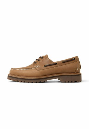 Bateaux en cuir marron avec un design à bout moc, des coutures blanches contrastantes, des œillets en métal et une semelle en caoutchouc texturée.
