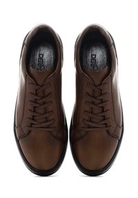 Zapatillas de cuero marrón con una textura suave, con un diseño clásico, puntera redonda y cordones oscuros. Las suelas de goma negra proporcionan durabilidad.