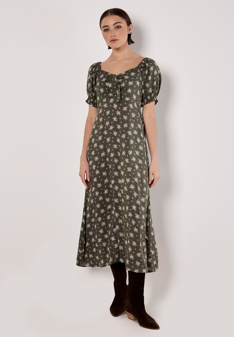 Robe midi fleurie verte avec de courtes manches bouffantes, décolleté carré et un détail à nouer à l'avant. Tissu lisse et jupe évasée.