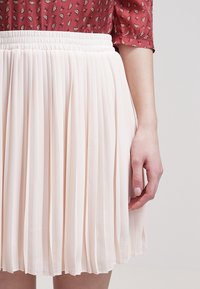 Gonna plissettata piacevole in tessuto rosa chiaro, con vita elastica, design fluido e preziosa texture con morbide pieghe.