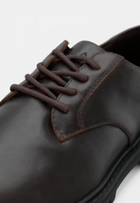 Dark brown polished leather dress shoe with matching brown laces and detailed stitching around the eyelets and sole.