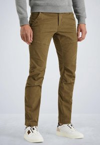 Pantalones cargo caqui con diseño tapered, que cuentan con bolsillos laterales y un tejido texturizado, combinados con zapatillas blancas y sudadera gris.