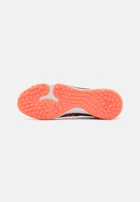 Sportschoen zool met een textuur van roze rubber, voorzien van cirkelvormige grip en een witte middenzool. Flexibele vorm met zichtbare groeven.