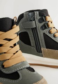 Wysokie buty sportowe, wykonane z czarnej siateczki oraz szarej syntetycznej skóry, z beżowym sznurowaniem, detalami zamka błyskawicznego oraz jasnobrązową podeszwą.