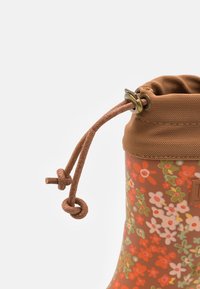 Botte de pluie en caoutchouc à motif floral marron avec bord en tissu marron et fermeture à cordon noué.