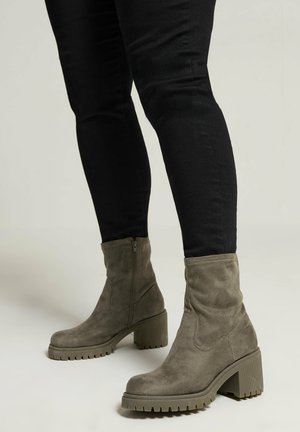 Grå ruskinds ankelstøvler med en rund tå, der har en kraftig hæl og en tekstureret gummisål; lynlåsdetaillering på siden.