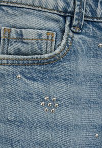 Hele sinise teksariidest kangas, millel on väike tasku, viimistletud kuldse õmblusega ja kaunistatud mustritena korraldatud hõbedaste naeltega.