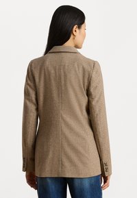 Bruine geblokte blazer met een op maat gemaakte pasvorm, revers met inkepingen en knoopmanchetten, gemaakt van een gestructureerde stof. De achteraanzicht toont strakke lijnen en ventilatieopeningen.