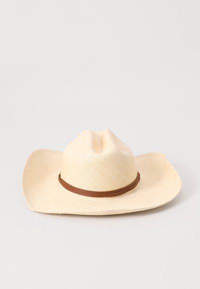 Wide-brimmed straw hat in natural beige, featuring a brown leather band. The crown has a subtle indentation and textured weave pattern.