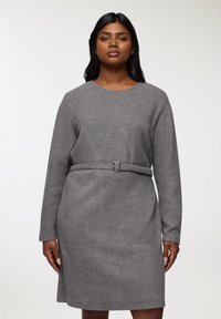 Abito grigio realizzato in un tessuto morbido e testurizzato, con scollatura rotonda, maniche lunghe e vita abbinata a una cintura con dettagli in argento.