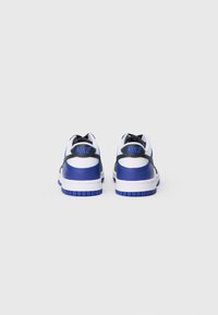 Sneakers Nike z białą cholewką i niebieskimi oraz czarnymi akcentami, teksturowanymi materiałami i wzorowaną podeszwą. Logo umieszczone z tyłu.