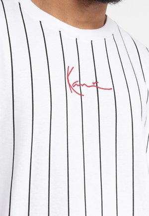 White shirt with thin black vertical stripes and red embroidered cursive text centered on the chest reading "Kane."