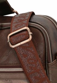 Braune Lederhandtasche mit strukturierter Oberfläche. Sie verfügt über einen breiten, gemusterten Stoffgurt und einen seitlichen Reißverschluss mit metallischen Beschlägen.