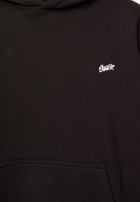 Schwarzer Kapuzenpulli mit einer vorderen Kängurutasche und kleinem weißen gestickten "SWT?" Logo auf der oberen linken Brust.