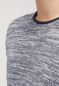 Pletený svetr s texturou, který má šedé a námořnicky modré pruhy, kulatý výstřih a námořnicky modrý žebrovaný lem na límci.