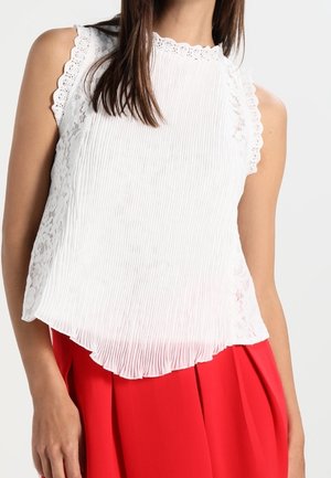 Wit mouwloos topje met een gestructureerd, geplooid ontwerp, een gescallopte kanten rand langs de halslijn en armsgaten, en een asymmetrische zoom.