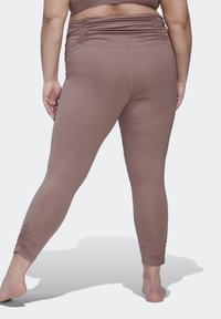 Bruine sportlegging met een gerimpelde tailleband en een gladde textuur, strakke pasvorm die naar de enkels toe versmalt, gemaakt van rekbare stof.