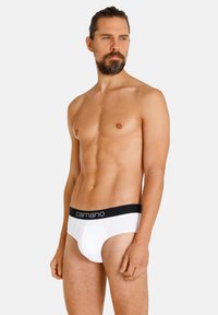Weiße Baumwollunterhose mit einem schwarzen elastischen Bund, auf dem der Markenname "camano" zu sehen ist, präsentiert an einem Modell vor einem neutralen Hintergrund.