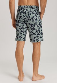 Blommönstrade shorts i ljusgrön och marinblå, med resårmidja och sidofickor, samt en slät tygtextur.
