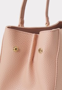 Rosa texturerad läderhandväska med två handtag upptill, prydd med guldfärgad metall och subtila sömdetaljer. Lättviktig design.