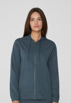 Sweatshirt à capuche zippé en bleu foncé. Il dispose d'une poche avant, de poignets côtelés et d'une texture douce et lisse. Cordons au niveau de la capuche.