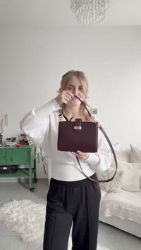 Burgundy leather handbag with gold hardware, rectangular shape, short handles, and a detachable shoulder strap. Textured surface is smooth.