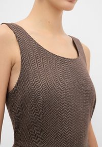 Robe sans manches à motif en chevrons marron avec un décolleté carré et une coupe ajustée, mettant en valeur une texture de tissu lisse et une silhouette structurée.