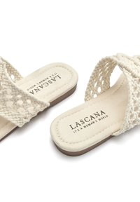 Sandales tissées beige avec des brides croisées, semelle intérieure douce et semelle texturée arborant le logo "LASCANA". Design lisse et décontracté.