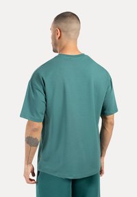 Camiseta de manga corta en verde menta con un corte relajado, confeccionada en una tela suave, que presenta un escote redondo y sin logotipos ni adornos visibles.